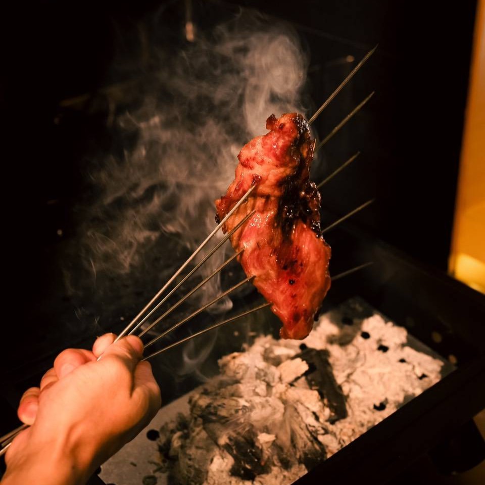 Chef Yuto Honoki expertly searing premium Iberico pork over high-quality charcoal at Waka Yuto Sukhumvit 51, infusing the dish with a delicate smoky aroma.