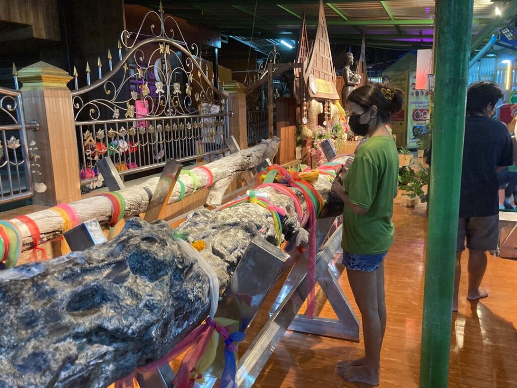 ワット・マハーブット：布が巻かれた御神木と供え物が並ぶ願掛けスポット