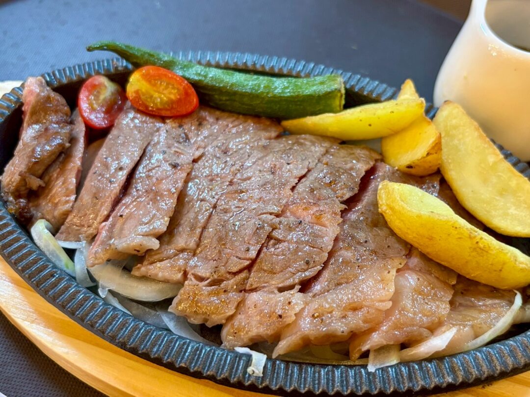  恵美須商店の鉄板ステーキ。一口大にカットされ、ポテト、オクラ、ミニトマトが添えられている。