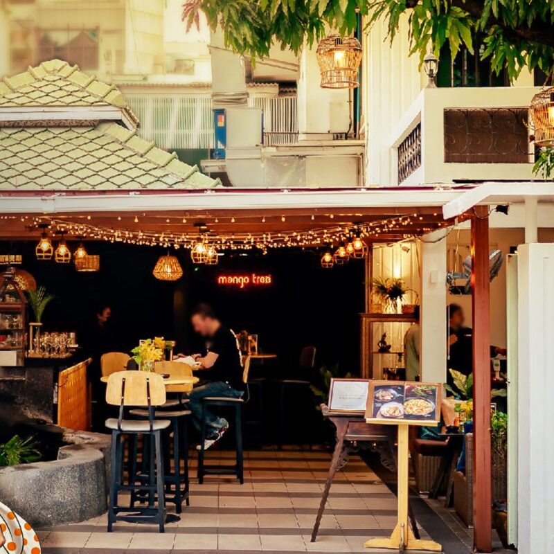 バンコク・スラウォン通りの人気タイ料理レストラン Mango Tree Surawong の外観と、テラス席で食事を楽しむ客の様子。
