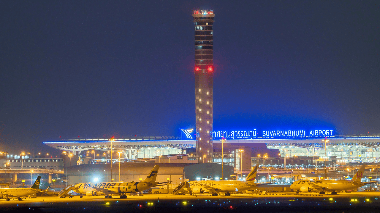 ライトアップされたスワンナプーム国際空港の管制塔と駐機する航空機の夜景。